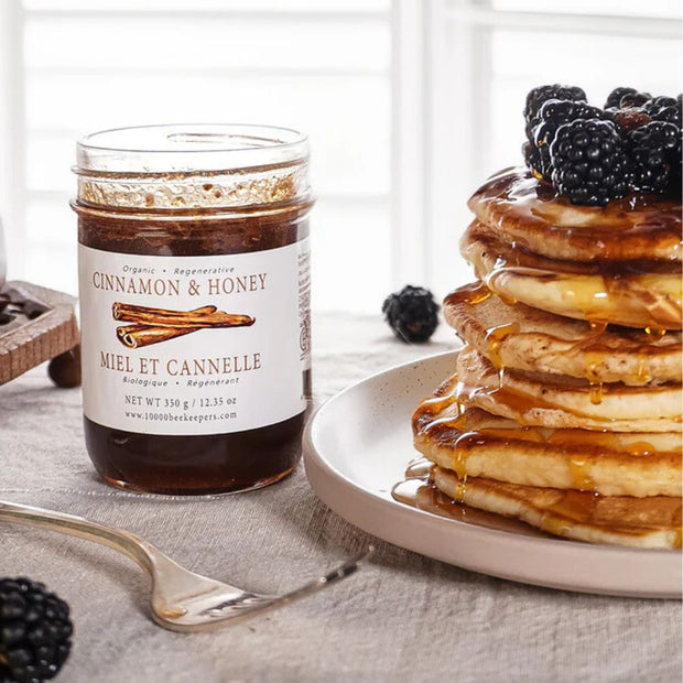 Cinnamon & Honey 12.3oz Jar by African Bronze Honey Co. next to a stack of pancakes