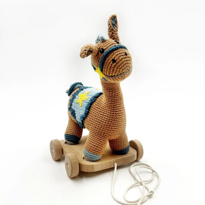 Crocheted brown horse toy with wooden wheels and a pull string