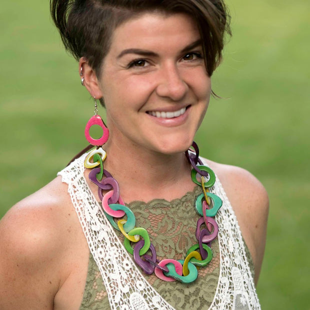 Woman wearing the tagua cadena necklace and earrings in pastel colors