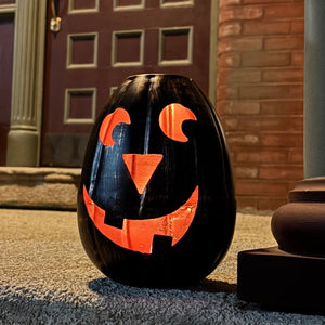 Black Metal Jack-o'-Lantern Votive Candle Holder lit up on a porch during Halloween