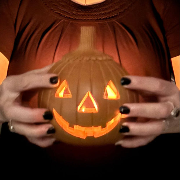 Person holding a Handmade Terracotta Jack O' Lantern lit up with a tea light in the dark