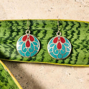 Mayura Teal & Red Dangle Earrings styled over green leaf