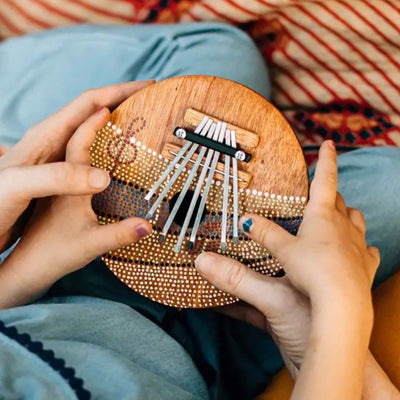 Little hands playing with a Summer Groove Coconut Shell Thumb Piano
