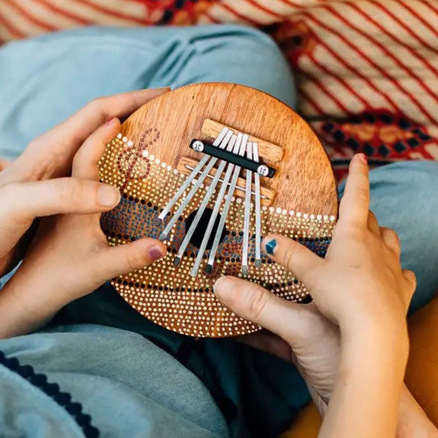 Little hands playing with a Summer Groove Coconut Shell Thumb Piano