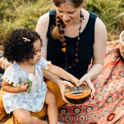 Mother and child holding a Summer Groove Coconut Shell Thumb Piano