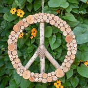 Galtang Vine and Wood Layered Peace Wreath hanging in front of a leafy wall