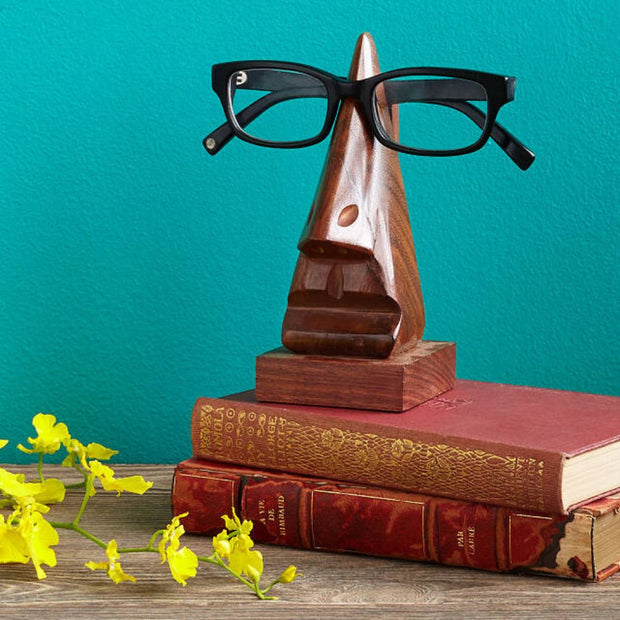 Wooden Nose Repose Eyeglass Holder styled on top of a stack of books