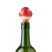 Wine bottle stopper shaped like a red mushroom on top of a wine bottle