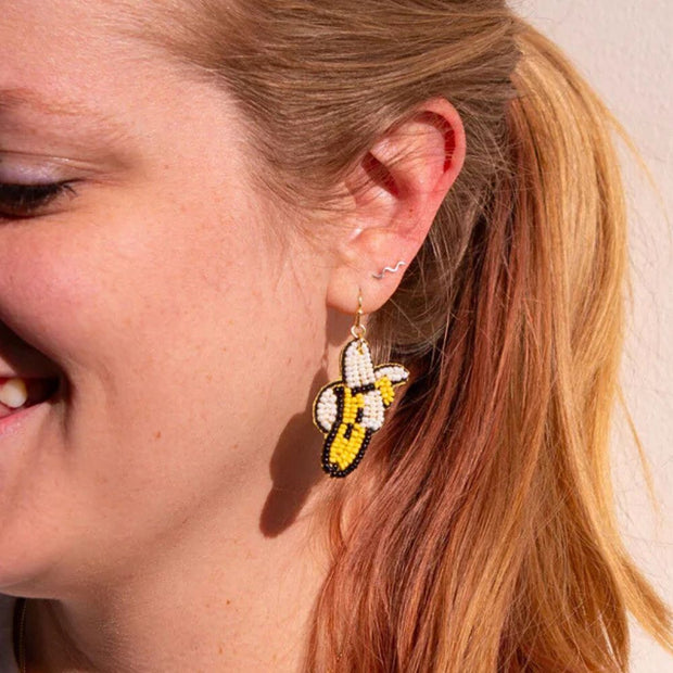 Close-up of a person wearing beaded banana dangle earrings