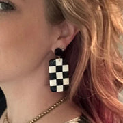Close-up of a person wearing a black and white checkered post earring.