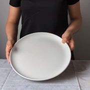 Stoneware Flat Dinner Plate Edan 11.2" Matte White held by model