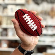 Hand holding a hand crocheted hacky sack football toy