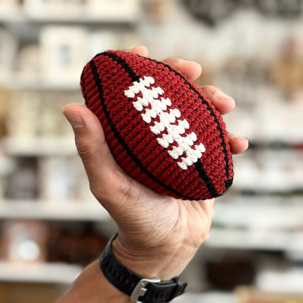 Hand holding a hand crocheted hacky sack football toy