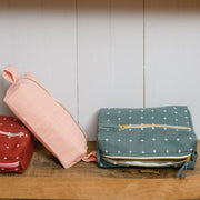 Grid-Stitch Utility Pouch Pencil Case - Pink next to a small toiletry bag