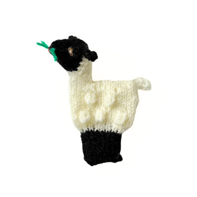 Knitted finger puppet depicting a Valais Blacknose Sheep chewing grass