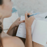 Person writing on a 5"x7" Monthly and Weekly  Floral Zodiac Constellation Planner