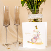 Floral Wedding Cake Quilled Greeting Card next to a couple of champagne flutes