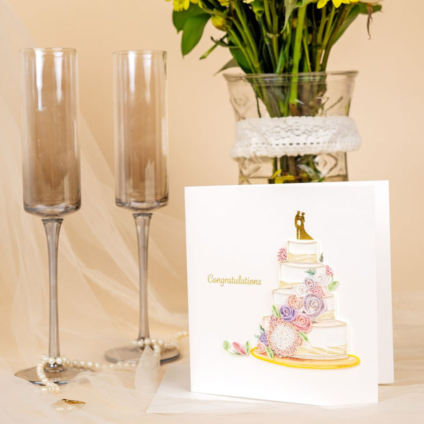 Floral Wedding Cake Quilled Greeting Card next to a couple of champagne flutes