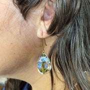 Female model wearing Clear Resin Dew Drop Earrings with suspended Forget-me-not Flowers