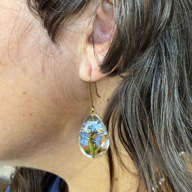 Female model wearing Clear Resin Dew Drop Earrings with suspended Forget-me-not Flowers