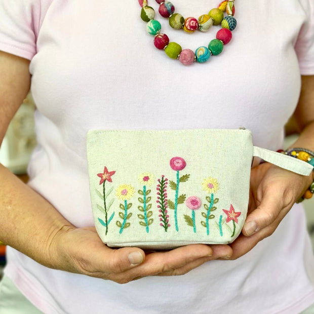 Small Wildflower Embroidered Cosmetic Pouch - cream in the hands of a model