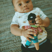 Baby holding a Pebble Child Pirate with Peg Leg Rattle Toy