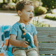 Pebble Child Dinosaur Rattle Toy - Petrol Blue with little boy