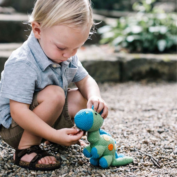 LIttle boy playing with a Pebble Green Dinosaur Rattle